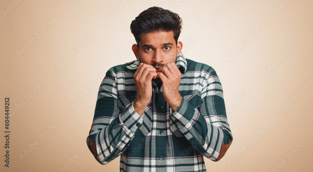 Stressed depressed indian man terrified about danger problems, suffering phobia, anxiety disorder, expresses fear, waving no, insecure, stress, panic. Hindu guy isolated on beige studio background Stressed depressed indian man terrified about danger problems, suffering phobia, anxiety disorder, expresses fear, waving no, insecure, stress, panic. Hindu guy isolated on beige studio background