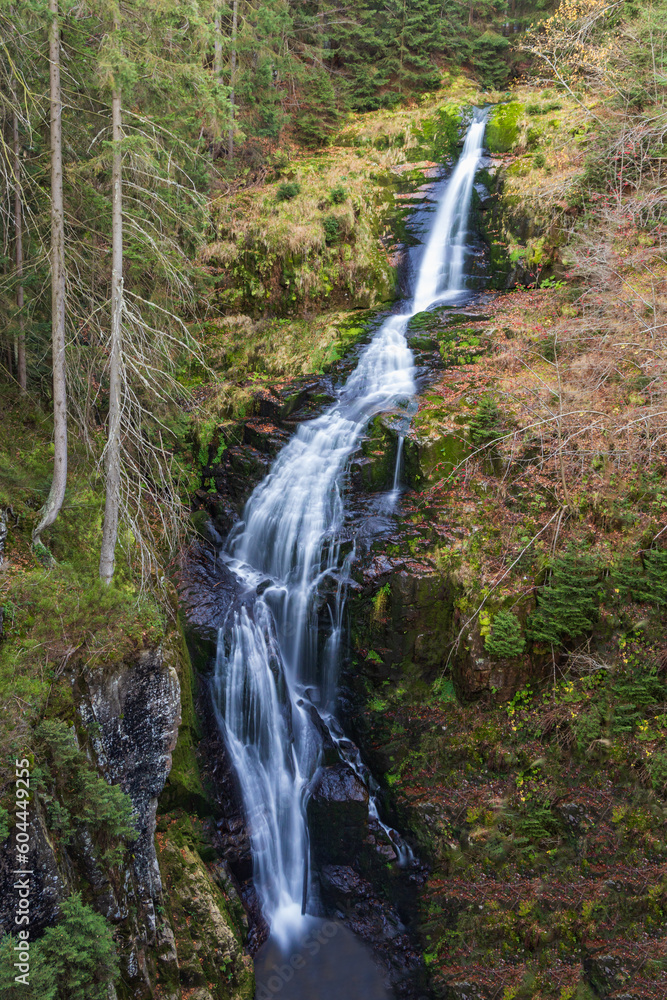 Beautiful long and narrow waterfall in mountains next to mountain trail and small shelter Beautiful long and narrow waterfall in mountains next to mountain trail and small shelter