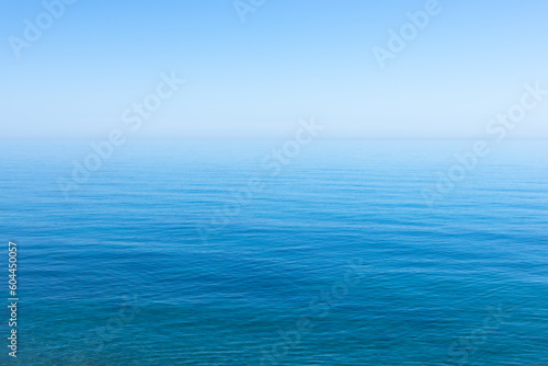 Ocean sky horizon line blends fading into infinity with blue turquoise colors of serene ocean waters and cloudless sky