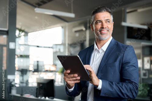 Fotografia Happy middle aged business man ceo wearing suit standing in office using digital tablet
