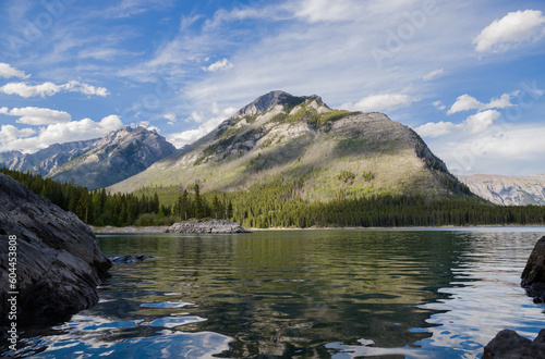 Lake Minnewanka, Banff National Park, Alberta, Canada, in summer - bue cloudy sky, mountains, small island in lake and calm clear spring water. concept - mountain tourism. copy space. 