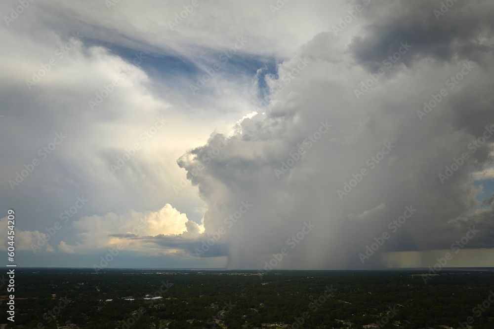 Dark stormy clouds forming on gloomy sky during heavy rainfall season over suburban town area Dark stormy clouds forming on gloomy sky during heavy rainfall season over suburban town area
