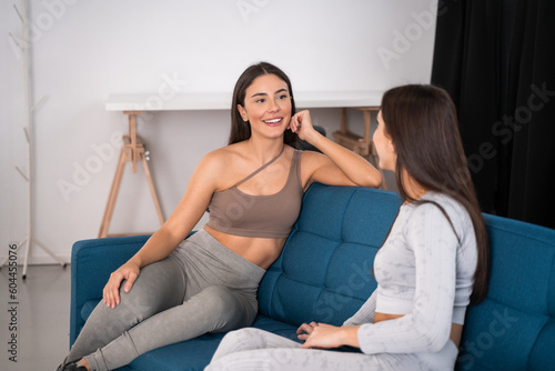 Portrait of excited sporty girls talking with good emotions while sitting on sofa