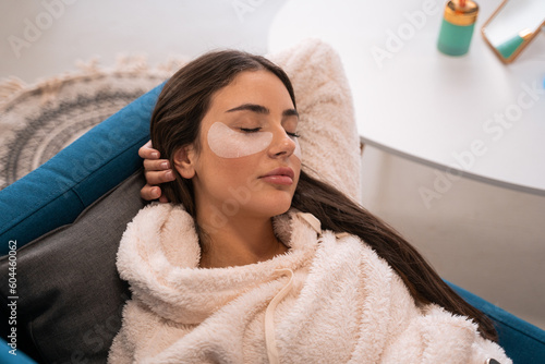 Relaxed woman with under eye patches laying at the sofa at home