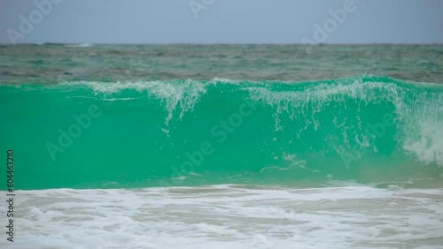 Ocean shorebreak in front view. Big beautiful green blue wave splashing with backwave and ready to break out. White foam sliding over sand. Beautiful sea waves. Beach sand and amazing sea.