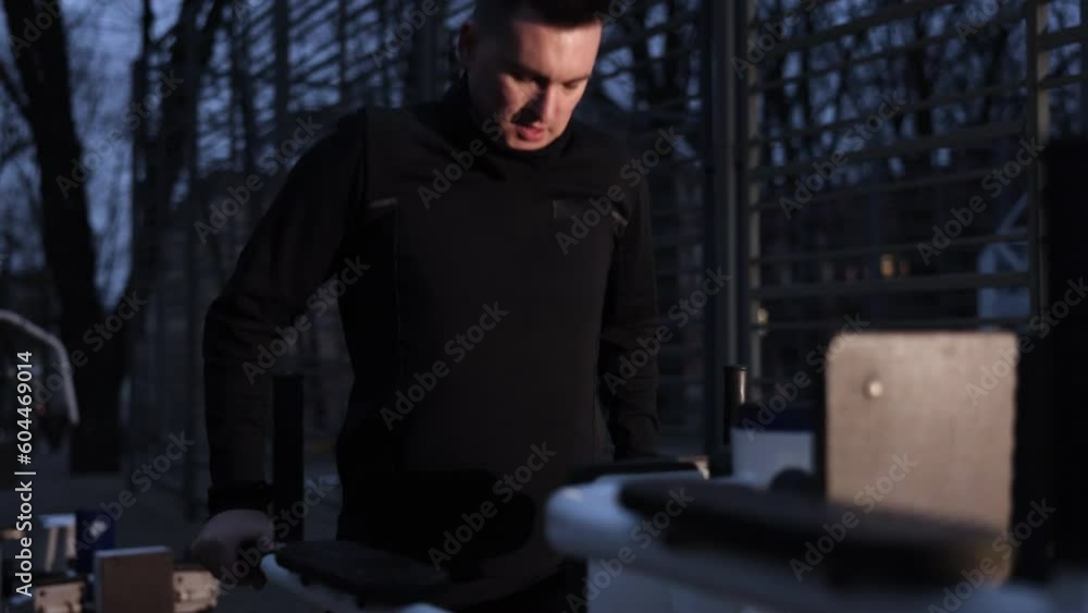 Exercises, Street sports, Evening workout. Young man exercises on street sports ground in evening by doing pull-ups on bars. Exercises, Street sports, Evening workout. Young man exercises on street sports ground in evening by doing pull-ups on bars.