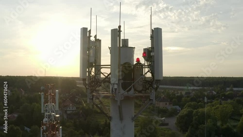 Drone flying around cell tower antennas, base station transmitting 5g, 4g signals in countryside.