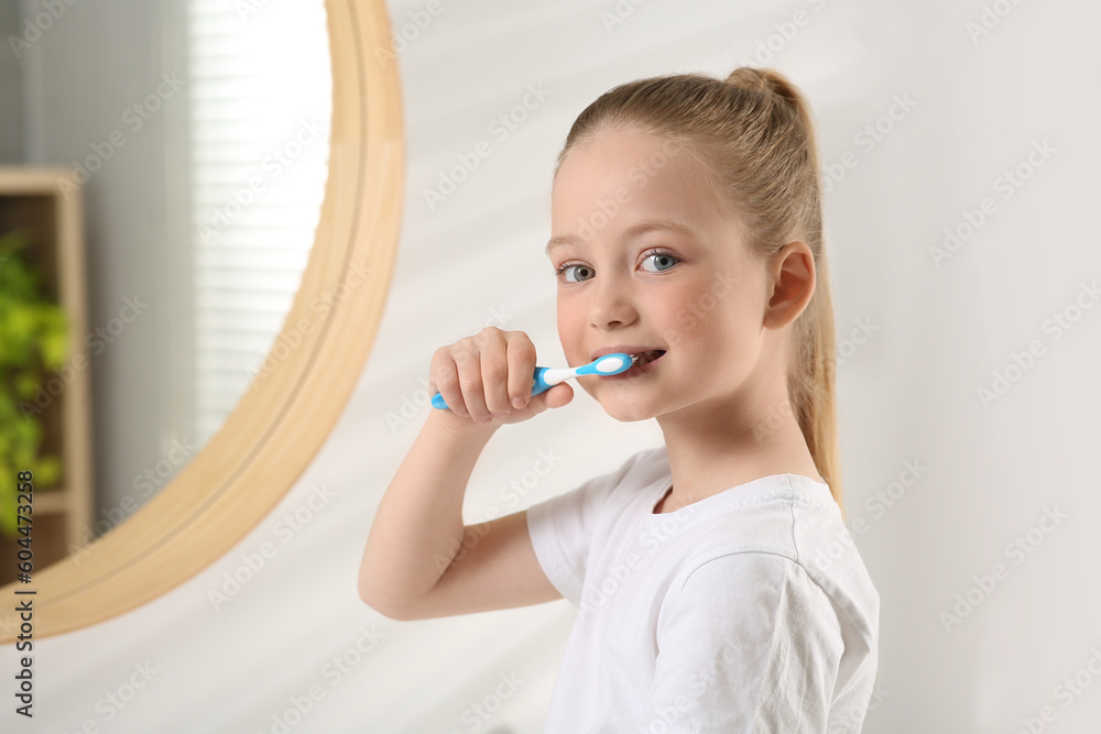 Cute little girl brushing her teeth with plastic toothbrush in bathroom, space for text Cute little girl brushing her teeth with plastic toothbrush in bathroom, space for text