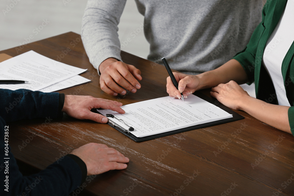 Notary helping couple with paperwork at wooden table, closeup Notary helping couple with paperwork at wooden table, closeup