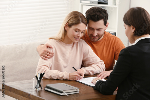 Professional notary helping couple with paperwork in office photo