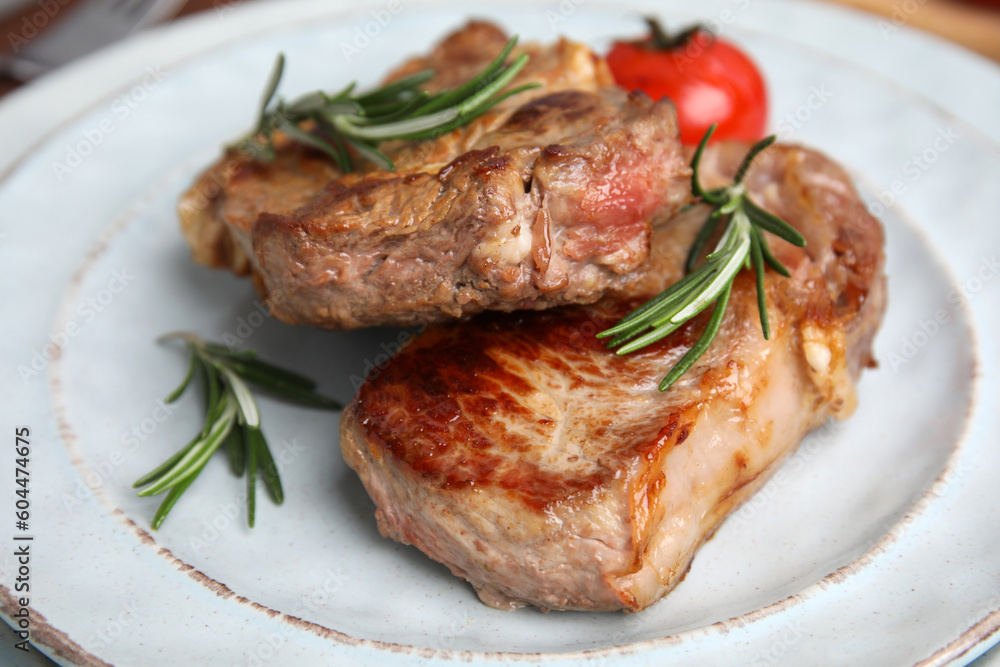 Delicious fried meat with rosemary and tomato on plate, closeup Delicious fried meat with rosemary and tomato on plate, closeup