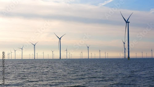 Windmill park in the sea, View of windmill turbines generating green energy electric in the Netherlands. Offshore farm windturbines against blue sky.