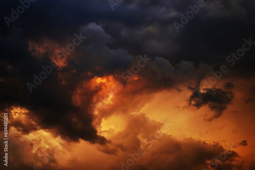Yellow orange red blue black sky with clouds. Dark cloudy dramatic ominous skies background. Fire, glow. Storm, hurricane, lightning. Or war, fear, armageddon, apocalypse, evil, horror concept.