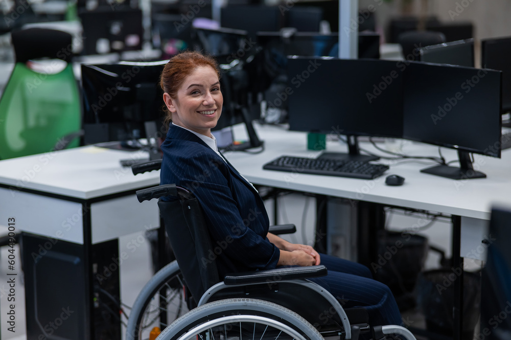 Caucasian smiling woman in wheelchair at work desk. 