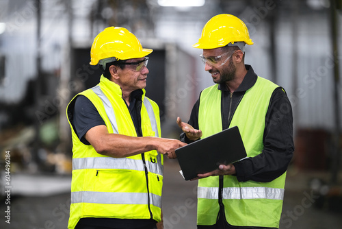 Fotografia technician, supervisor with a senior foreman holding a walkie-talkie to command or inspect work with a checklist computer The background is an industrial warehouse