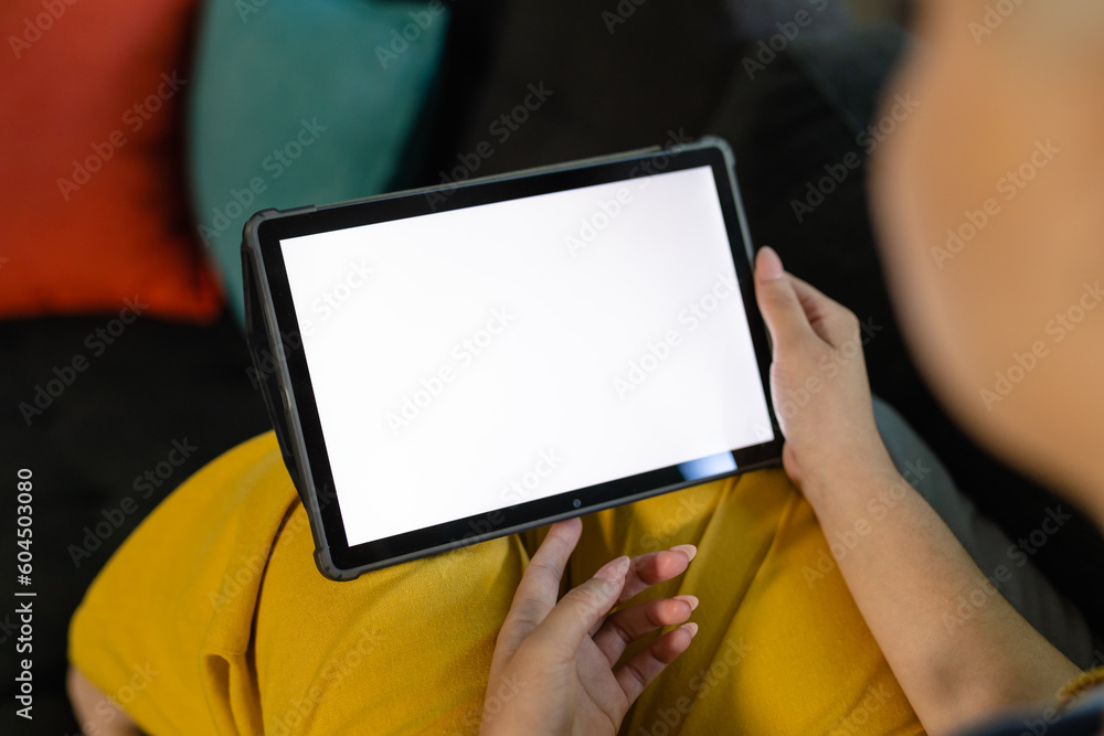 Biracial woman sitting on sofa and using tablet with copy space on screen