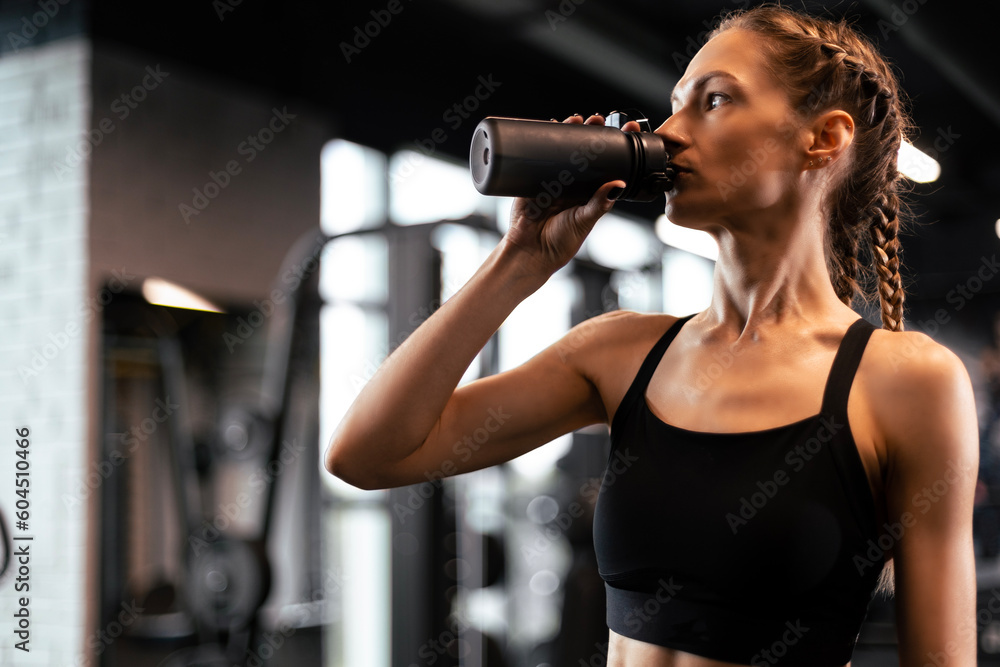 Sporty woman resting, drinking water, having break after doing exercise