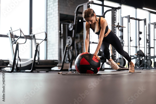 Beautiful fitness woman doing mountain climber exercises with medecine ball at gym.