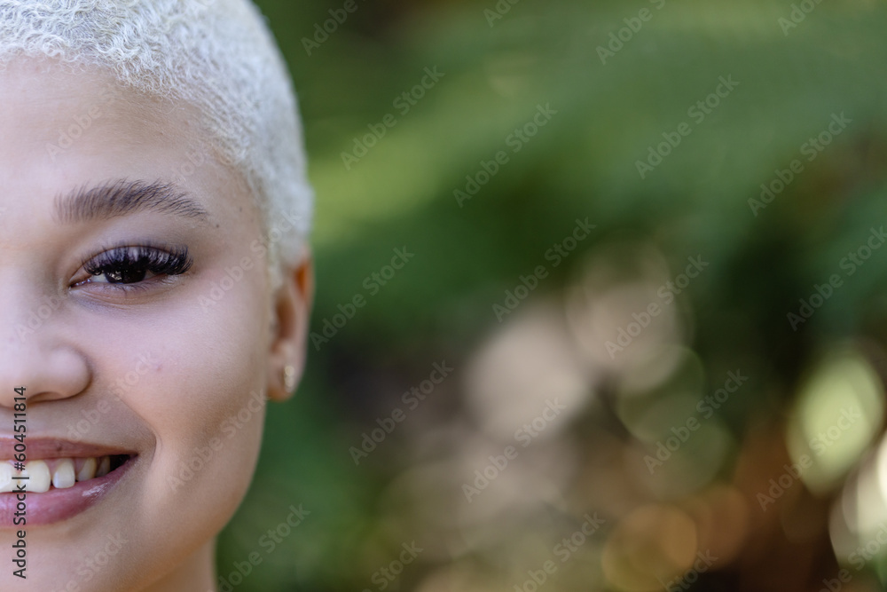Unaltered half portrait of biracial woman with short bleached hair in garden smiling, copy space Unaltered half portrait of biracial woman with short bleached hair in garden smiling, copy space