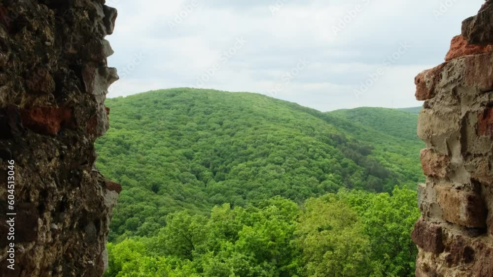 Scenic view from the window of the old brick fortress on the surrounding mountain landscape. Part of the medieval defense building. Historical landmarks tourism. Scenic view from the window of the old brick fortress on the surrounding mountain landscape. Part of the medieval defense building. Historical landmarks tourism.