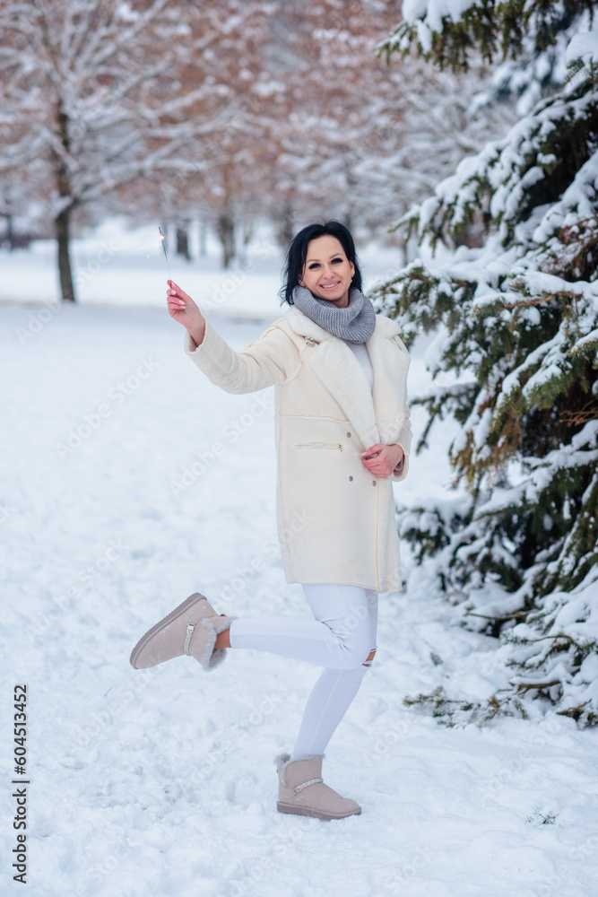 beautiful girl in winter in a cold forest under the snow with a sparkler in her hands beautiful girl in winter in a cold forest under the snow with a sparkler in her hands