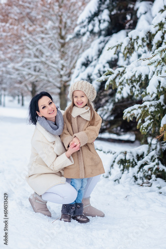 little girl with mom joyfully in winter in frosty forest under snow. Family in the winter forest on a frosty day. mother hugging daughter