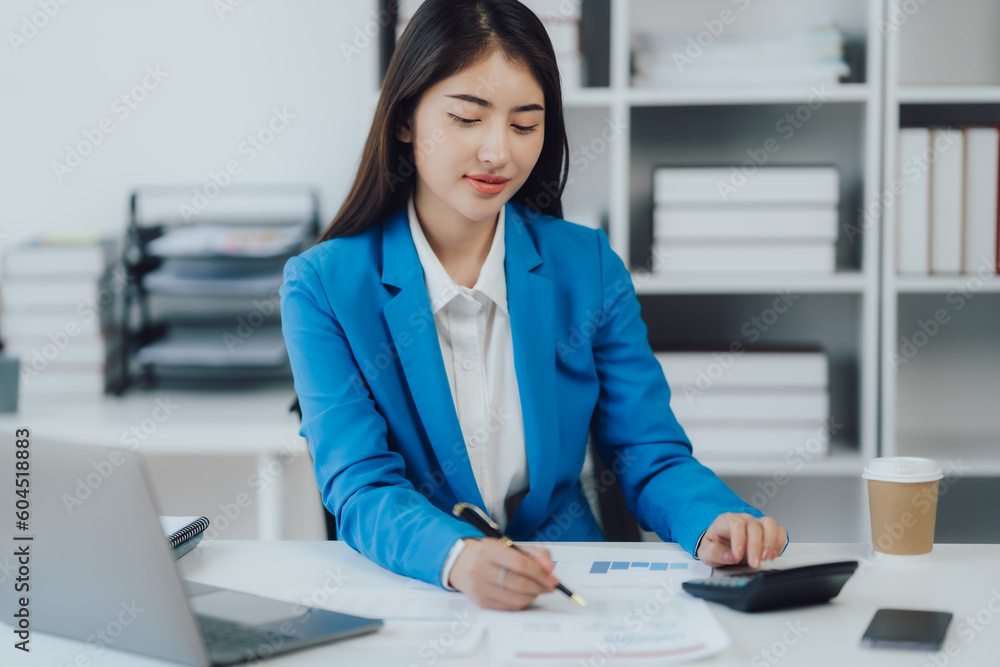 Asian Business woman using calculator and laptop for doing math finance on an office desk, tax, report, accounting, statistics, and analytical research concept Asian Business woman using calculator and laptop for doing math finance on an office desk, tax, report, accounting, statistics, and analytical research concept
