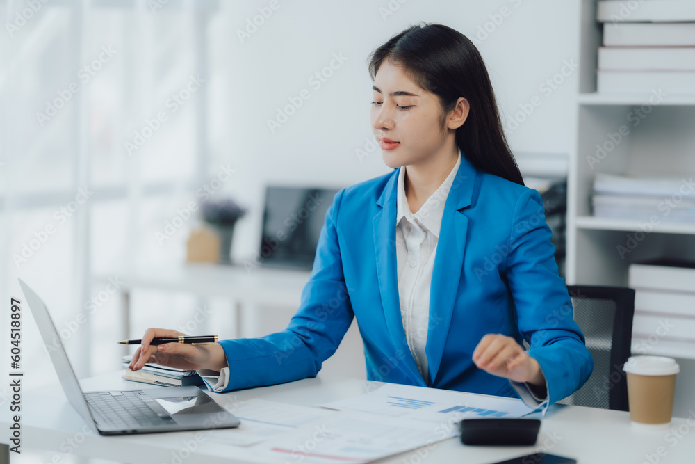 Asian Business woman using calculator and laptop for doing math finance on an office desk, tax, report, accounting, statistics, and analytical research concept Asian Business woman using calculator and laptop for doing math finance on an office desk, tax, report, accounting, statistics, and analytical research concept