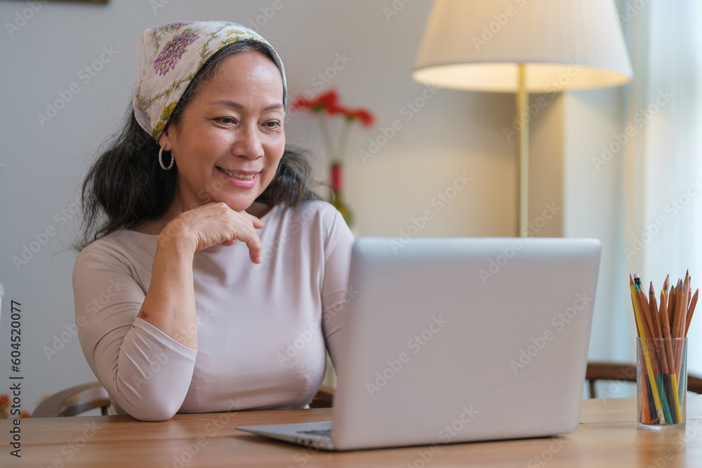 Beautiful stylish elderly woman sitting at desk in cozy home interior and using laptop. Beautiful stylish elderly woman sitting at desk in cozy home interior and using laptop.