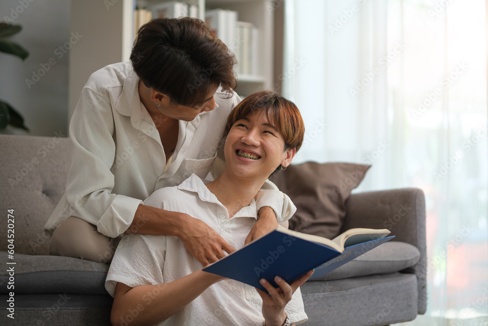 Happy young gay couple reading book, spending time happiness moment together at home. LGBT, gay couple relationship lifestyle concept. Happy young gay couple reading book, spending time happiness moment together at home. LGBT, gay couple relationship lifestyle concept.