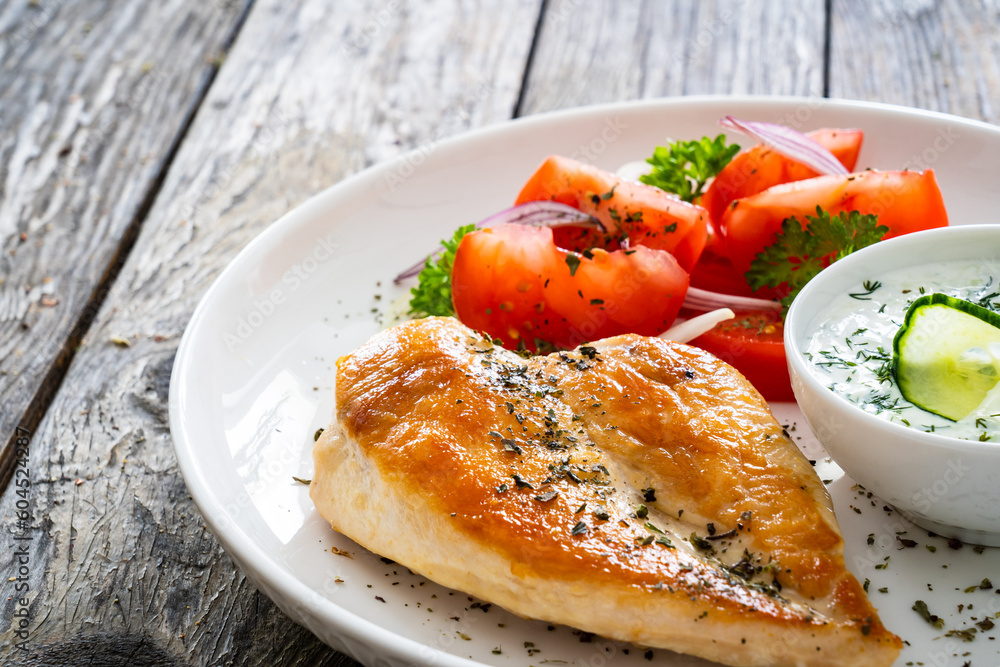 Seared chicken breast and tzatziki on wooden table Seared chicken breast and tzatziki on wooden table