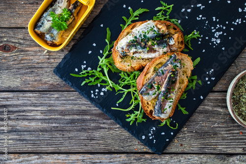 Tasty sandwiches - toasted bread with smoked sardine and arugula on wooden table