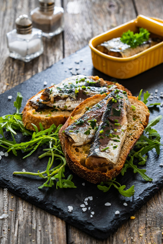 Tasty sandwiches - toasted bread with smoked sardine and arugula on wooden table