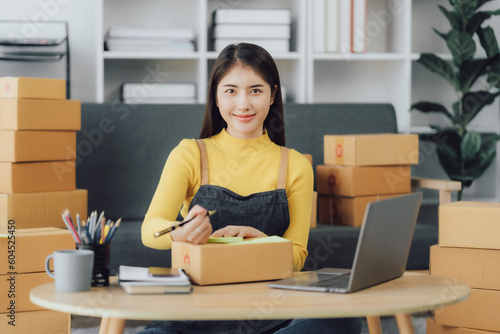 tarting Small business entrepreneur SME freelance,Portrait young woman working at home office, BOX,smartphone,laptop, online, marketing, packaging, delivery, SME, e-commerce concept