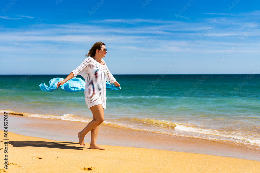 Beautiful woman walking on sunny beach holding shawl
Beautiful woman walking on sunny beach holding shawl