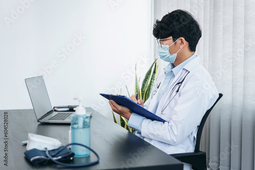 Male doctor in face mask medical using laptop to searching infor