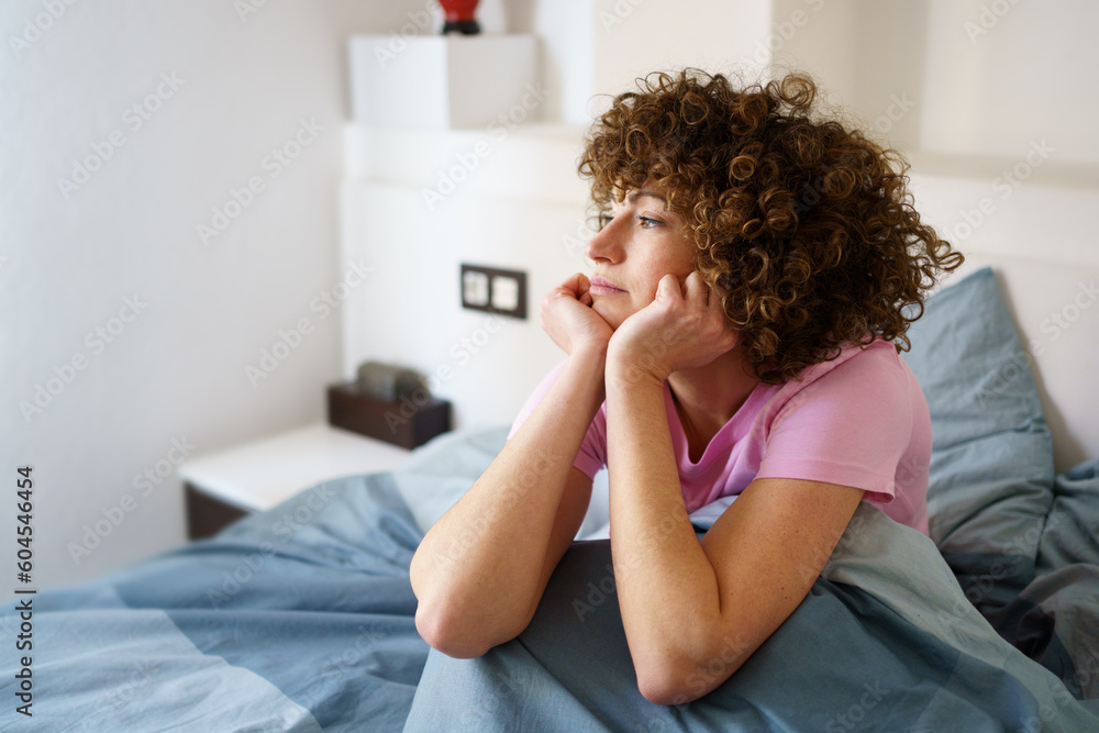 Dreamy lady sitting on bed in morning Dreamy lady sitting on bed in morning
