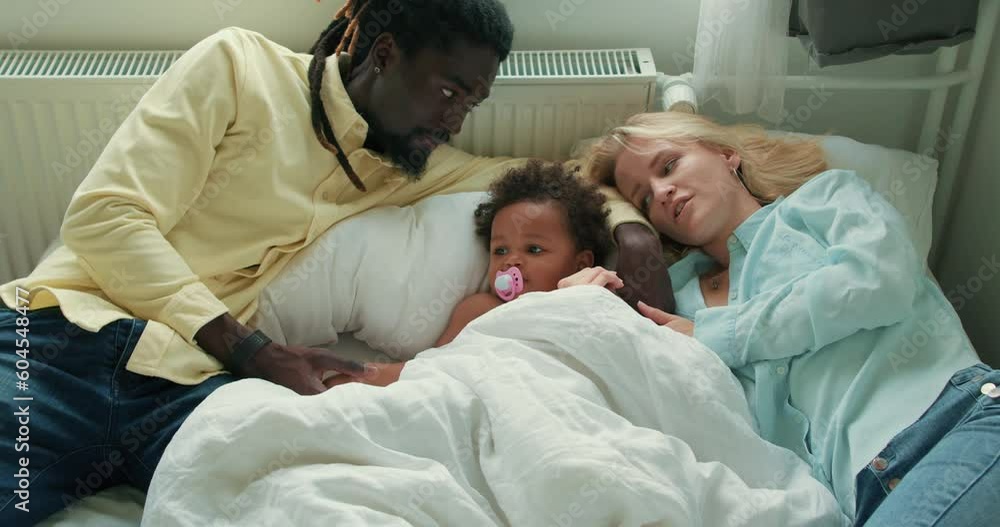 Family bonding time. African American and Caucasian parents with daughter on bed. Happy international family lying in living room Slow motion Love Relationship lifestyle Family bonding time. African American and Caucasian parents with daughter on bed. Happy international family lying in living room Slow motion Love Relationship lifestyle