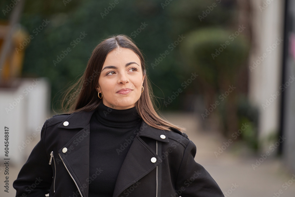 Fototapeta premium portrait of smiling brunette woman with pensive face in the city