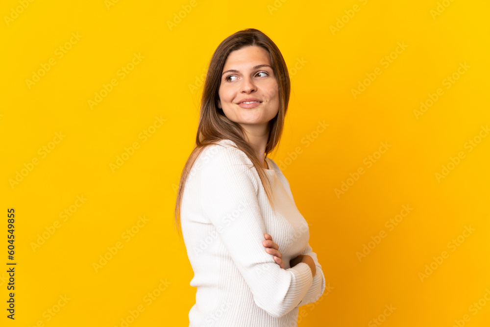 Obraz premium Young Slovak woman isolated on yellow background looking to the side and smiling