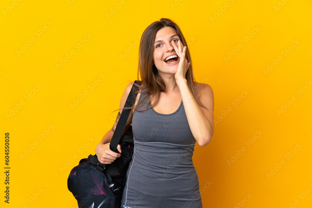 Slovak sport woman with sport bag isolated on yellow background shouting with mouth wide open Slovak sport woman with sport bag isolated on yellow background shouting with mouth wide open