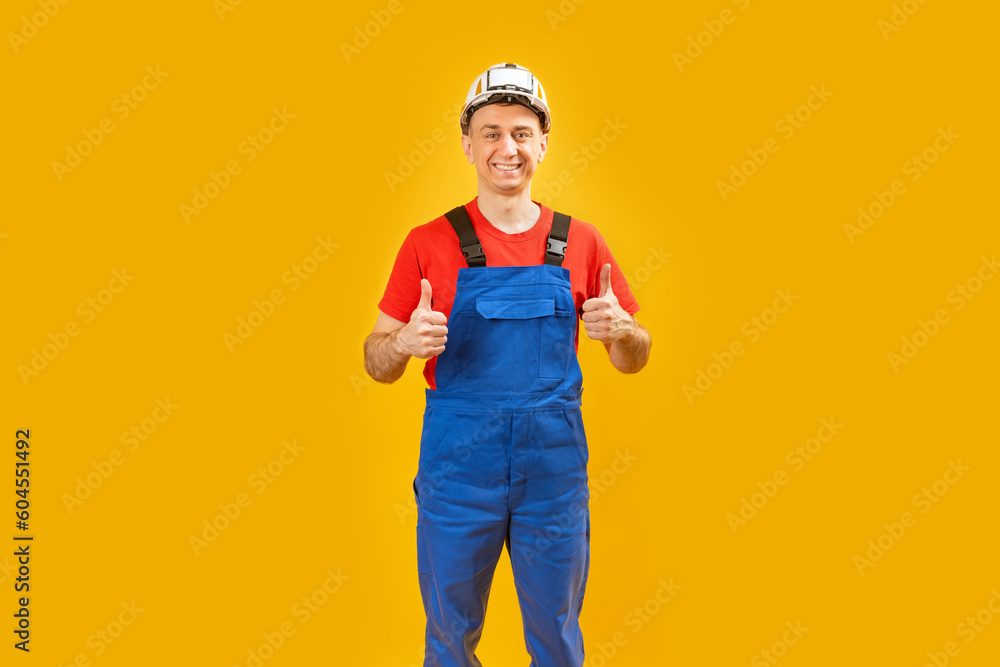 Smiling architect man or engineer on isolated yellow background shows thumbs up and smile. Copy space. Smiling architect man or engineer on isolated yellow background shows thumbs up and smile. Copy space.
