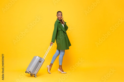 Slika na platnu Fashionable skinhead African American woman traveler walking with trolley bag re