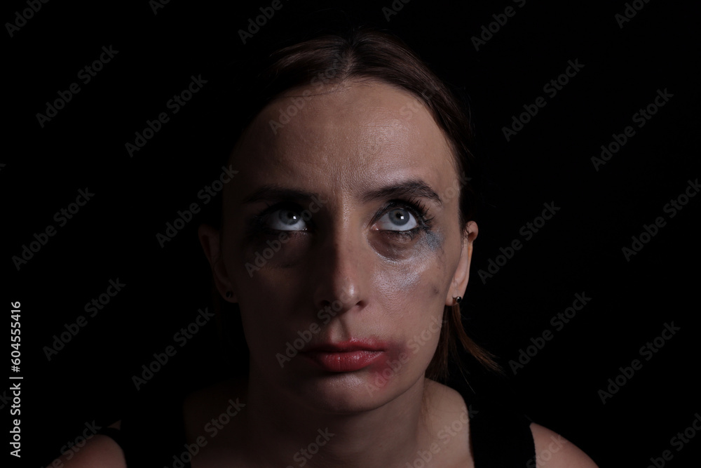 Upset crying woman with smeared mascara and lipstick on black background
