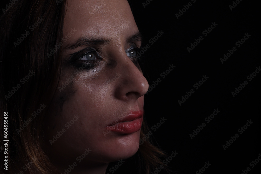 Upset crying woman with smeared mascara and lipstick on black background Upset crying woman with smeared mascara and lipstick on black background