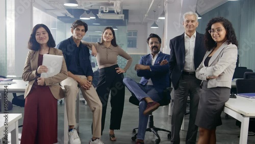 A happy smiling confident team or group of diverse multiethnic male and female corporate office executives or colleagues together posing and looking at the camera in modern start up business workspace