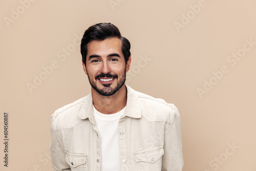 Portrait of a stylish man smile closeup on a beige background in a white t-shirt, fashionable clothing style, copy space