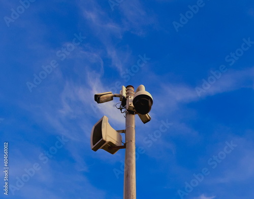 close up of CCTV tower and loudspeaker in park with blue sky background