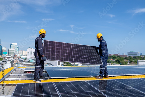 Engineers walking on roof inspect check and Maintenace solar cell panel by hold blue print ,solar cell is smart grid ecology energy sunlight alternative power factory concept.