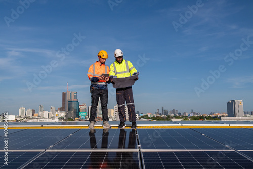 Engineers walking on roof inspect check and Maintenace solar cell panel by hold blue print ,solar cell is smart grid ecology energy sunlight alternative power factory concept.